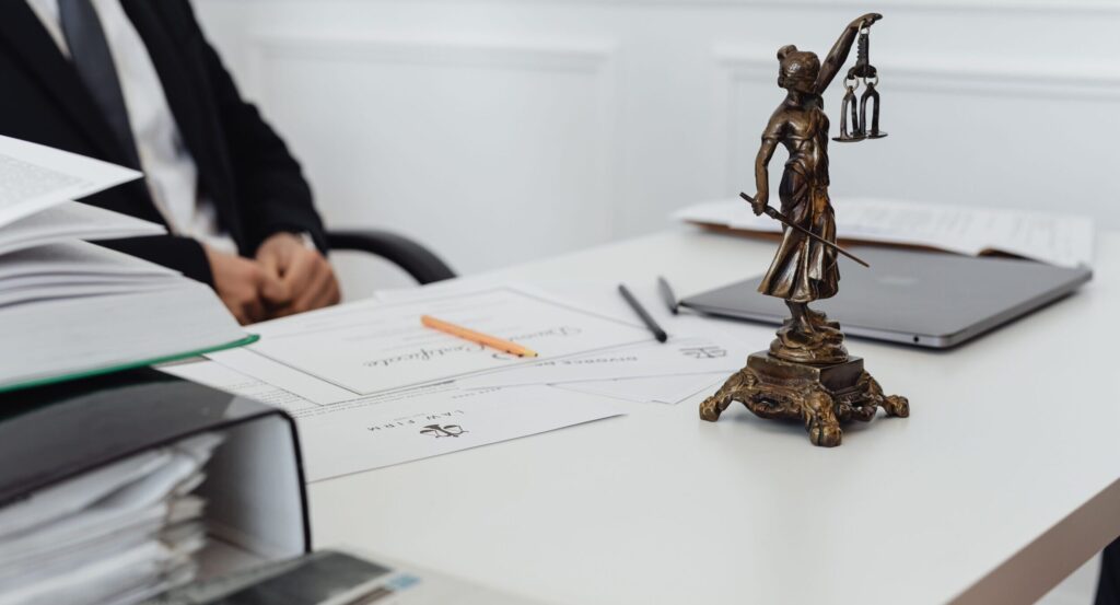 A legal professional's workspace featuring Lady Justice statue, documents, and a laptop.